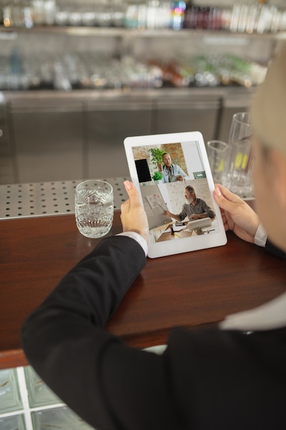 uomo che utilizza tablet per videochiamata mentre si beve acqua