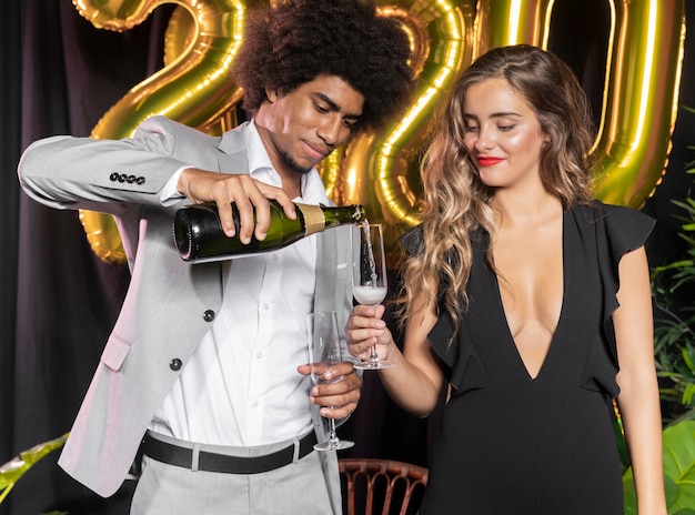 Uomo che versa champagne in vetro tenuto da donna