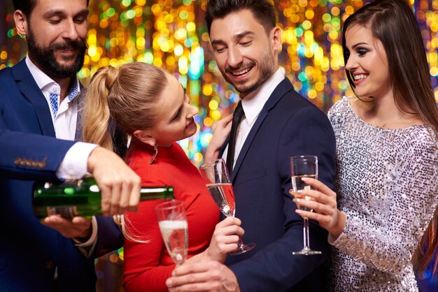 Uomo che versa champagne per i suoi amici