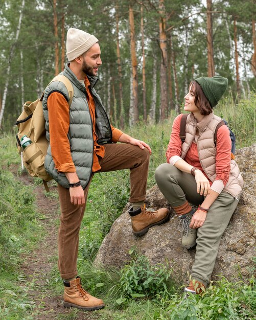 Uomo completo del colpo che esamina la ragazza che si siede sulla roccia