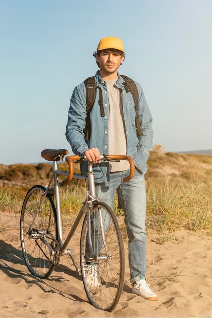 Uomo completo del colpo con la bicicletta alla spiaggia