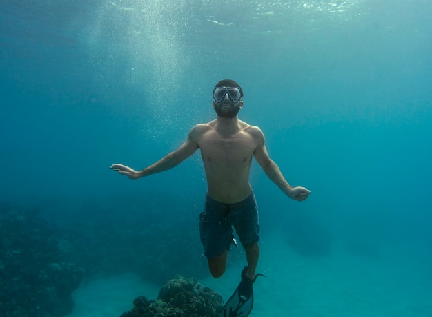 Uomo con attrezzatura subacquea nuotare nell'oceano