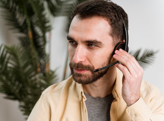 Uomo con auricolare che ha videochiamata sul computer portatile