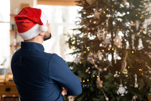 Uomo con Babbo Natale guardando l'albero di Natale
