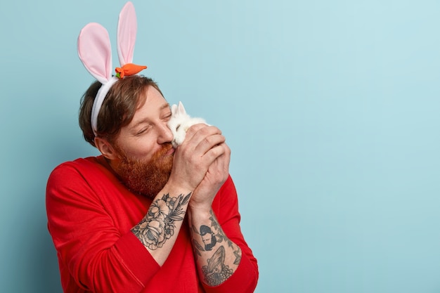 Uomo con barba allo zenzero che indossa abiti colorati e orecchie da coniglio