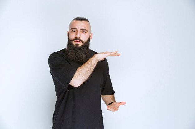 Uomo con barba che mostra le dimensioni di un oggetto.