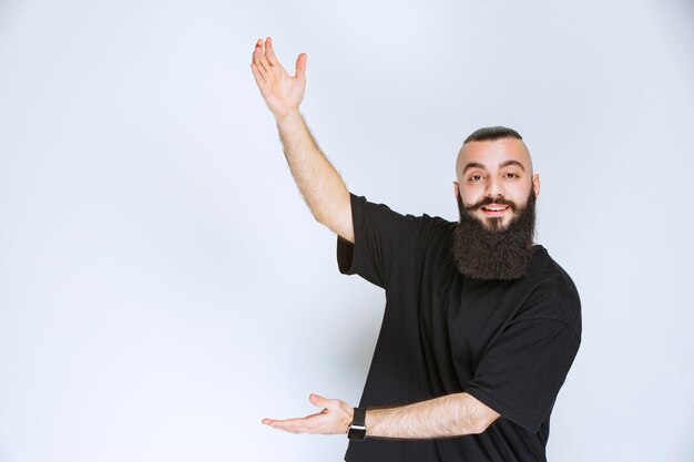 Uomo con barba che mostra le dimensioni di un oggetto.