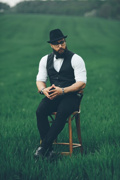 Uomo con barba e occhiali da sole nel campo verde