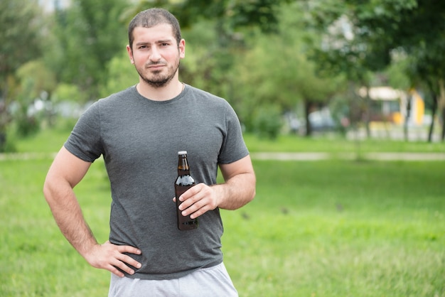 Uomo con birra in piedi nel parco
