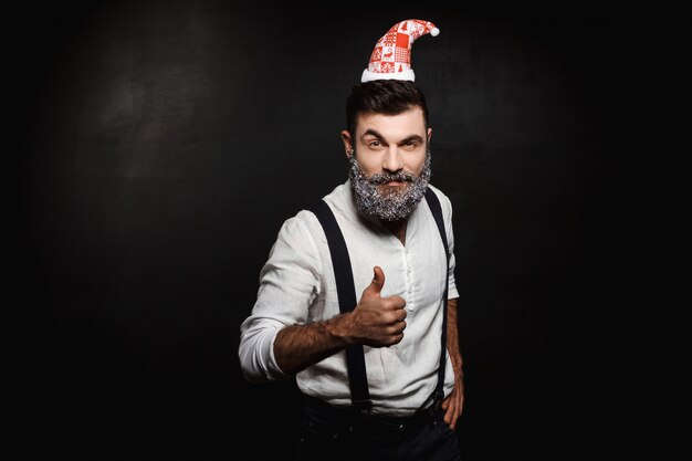 Uomo con cappello di Babbo Natale che mostra bene sul nero.