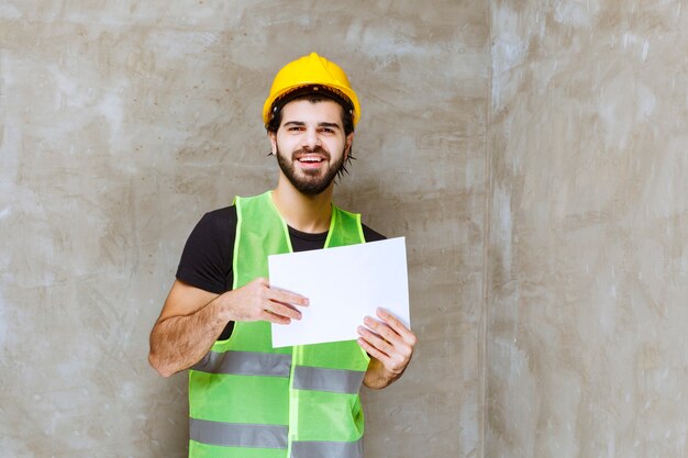 Uomo con casco giallo e attrezzatura che tiene i rapporti sul progetto