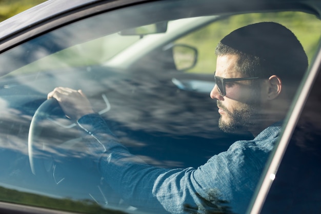 Uomo con gli occhiali da sole alla guida di auto