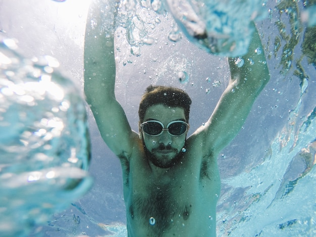 Uomo con gli occhiali da sole che si tuffano in piscina
