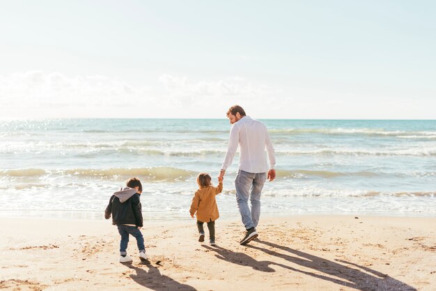 Uomo con i bambini che camminano verso il mare