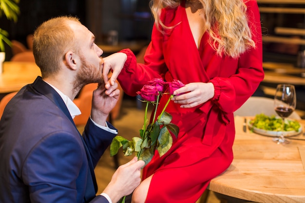 Uomo con i fiori che bacia la mano della donna