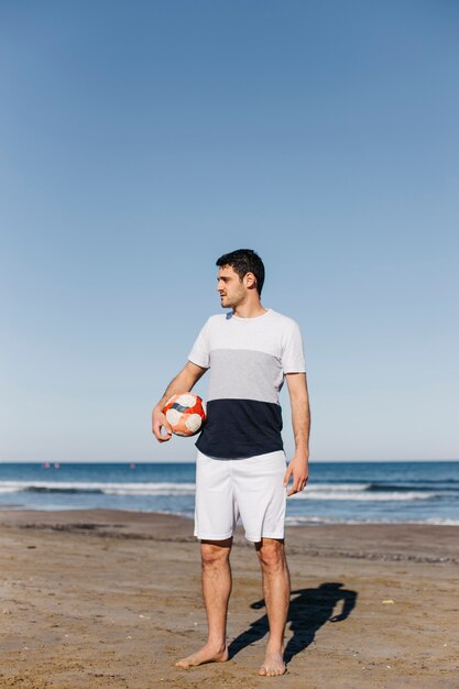 Uomo con il calcio in spiaggia