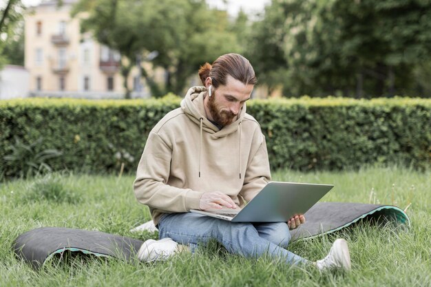 Uomo con il computer portatile nel parco della città