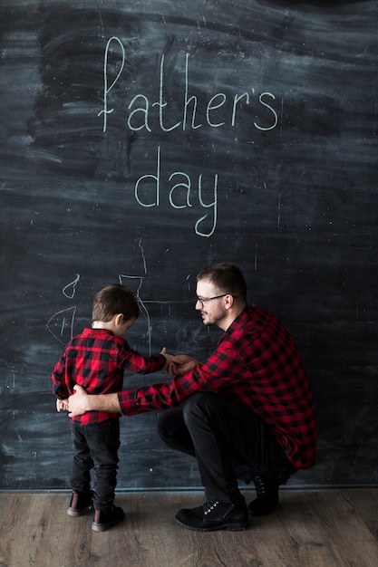 Uomo con il figlio il giorno di padri davanti alla lavagna