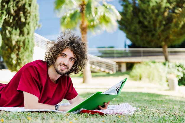 Uomo con il libro di testo che si trova sulla terra del parco