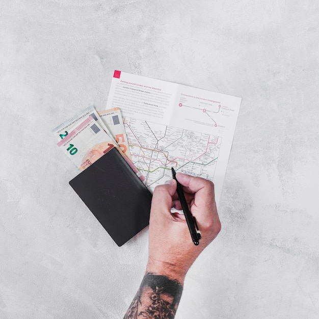 Uomo con il passaporto e le banconote in euro che segnano sulla mappa stradale