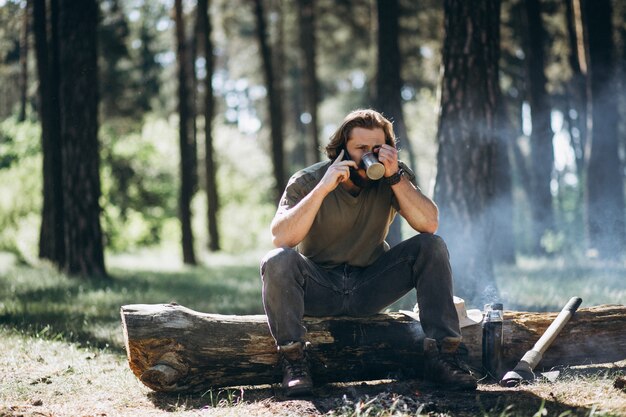 Uomo con il telefono dal falò nella foresta