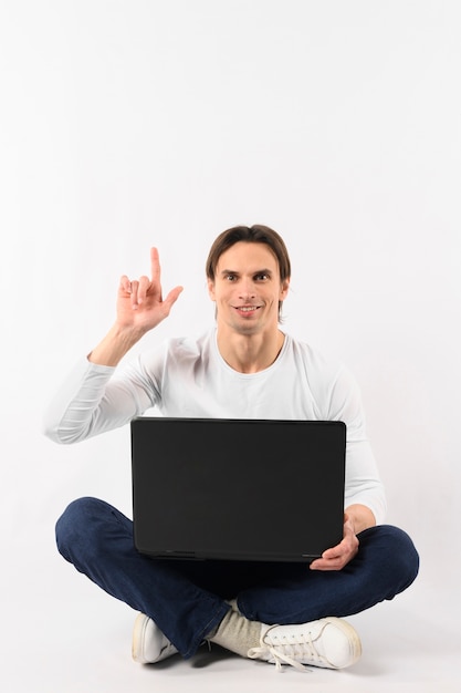 Uomo con indicare del computer portatile