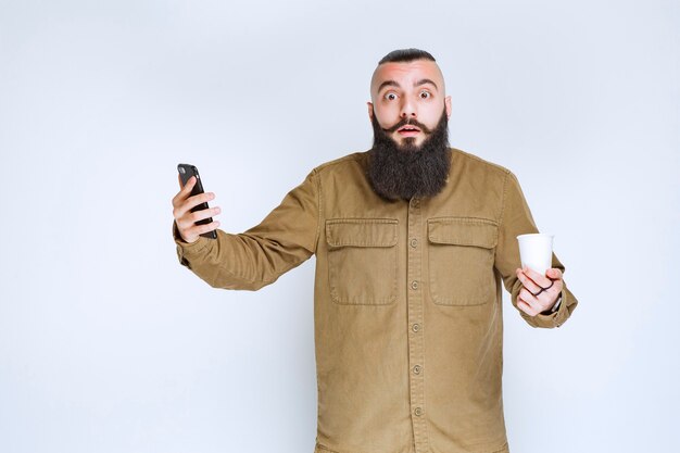 Uomo con la barba che controlla i suoi messaggi con sorpresa.