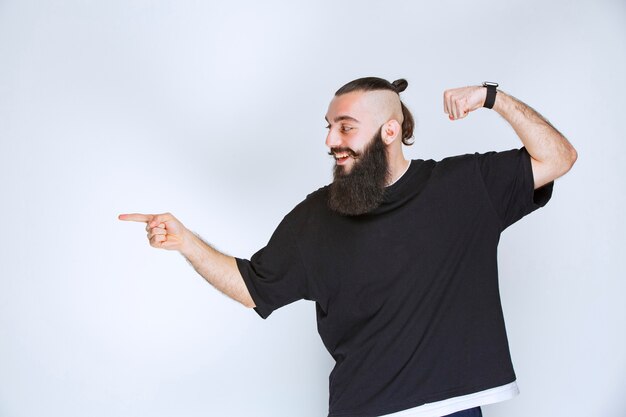 Uomo con la barba che dimostra i suoi muscoli e pugni del braccio.