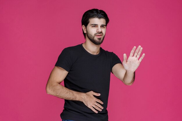 Uomo con la barba che fa il segno della mano di rifiuto