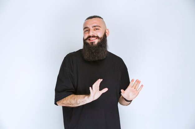 Uomo con la barba che ferma qualcosa con la mano aperta.