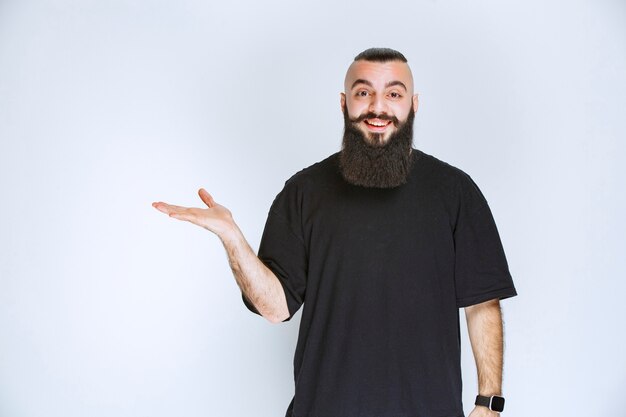 Uomo con la barba che indica qualcuno intorno.