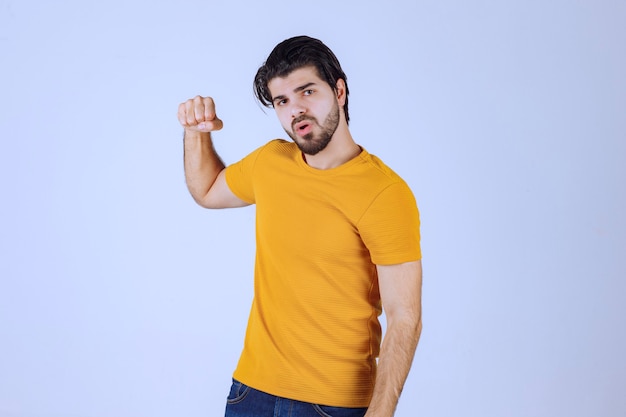 Uomo con la barba che mostra i muscoli del pugno e del braccio e si sente potente