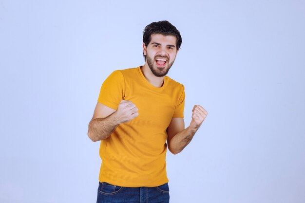 Uomo con la barba che mostra i muscoli del pugno e del braccio e si sente potente