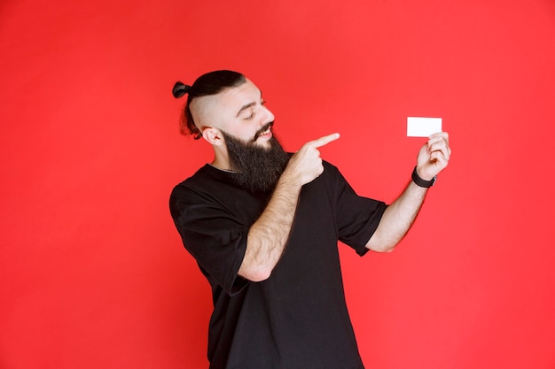 Uomo con la barba che presenta il suo biglietto da visita.