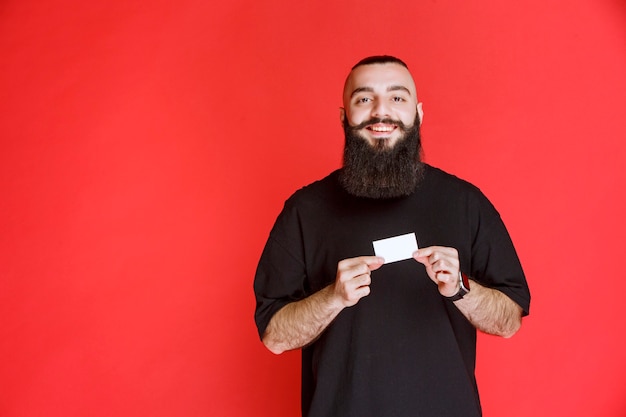 Uomo con la barba che presenta il suo biglietto da visita.