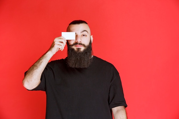 Uomo con la barba che presenta il suo biglietto da visita.