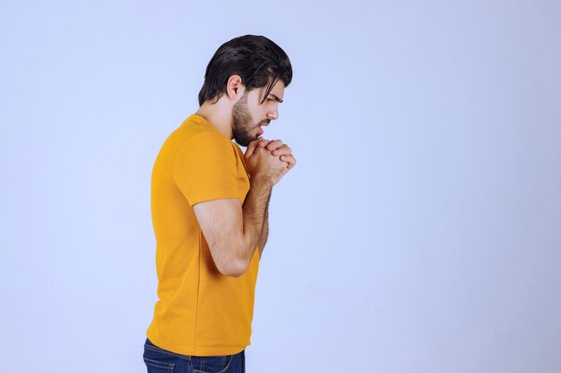 Uomo con la barba che unisce le mani e prega e chiede qualcosa