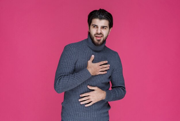 Uomo con la barba nera che rifiuta qualcosa.