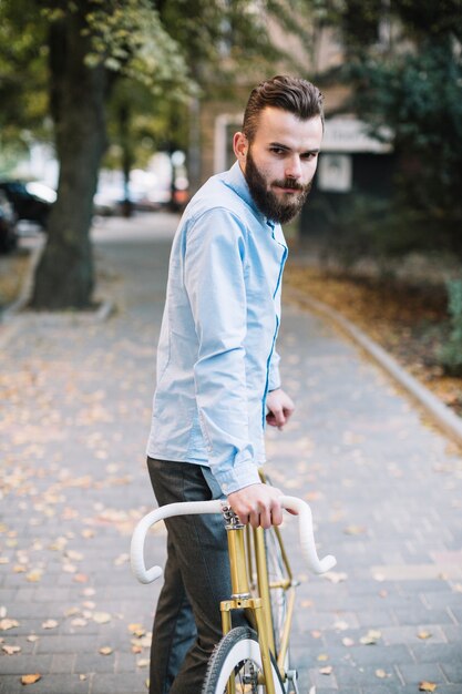 Uomo con la bicicletta che guarda l&#39;obbiettivo