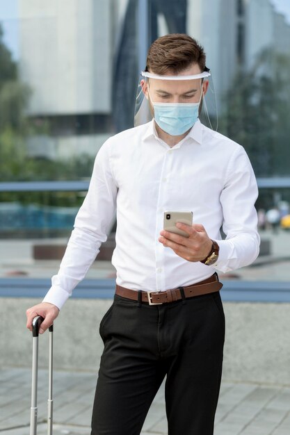 Uomo con la maschera che controlla mobile