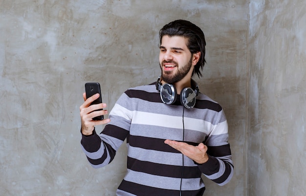 Uomo con le cuffie che controlla i suoi messaggi o la sua playlist musicale con energia positiva