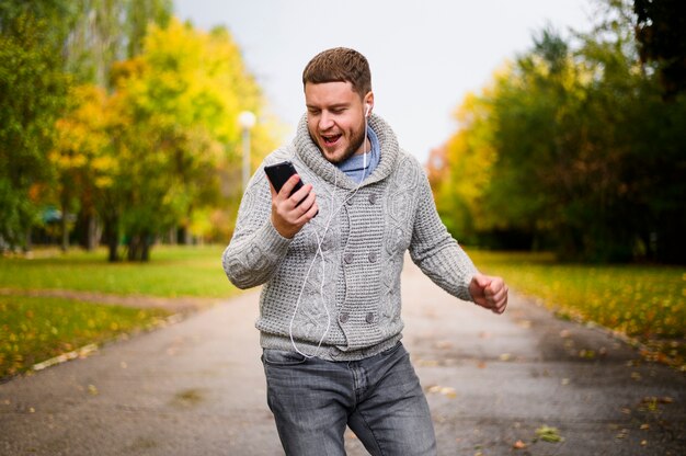 Uomo con lo smartphone e le cuffie su un vicolo nel parco