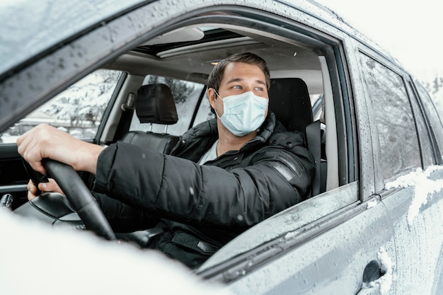 Uomo con maschera medica alla guida di auto per un viaggio su strada