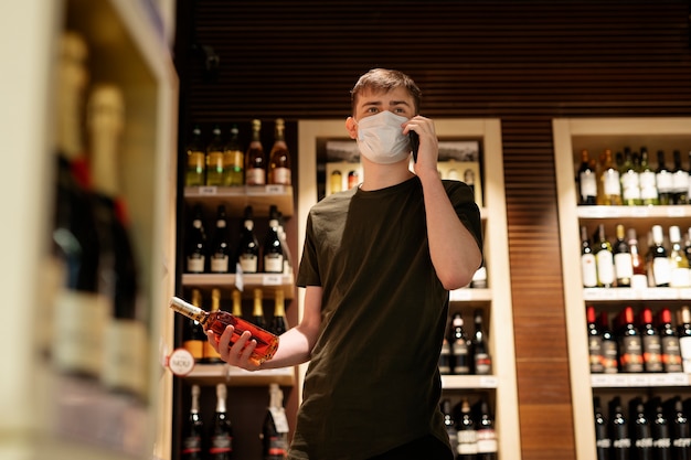 Uomo con maschera medica che fa la spesa al supermercato