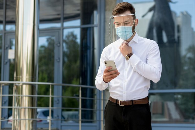 Uomo con maschera utilizzando il cellulare