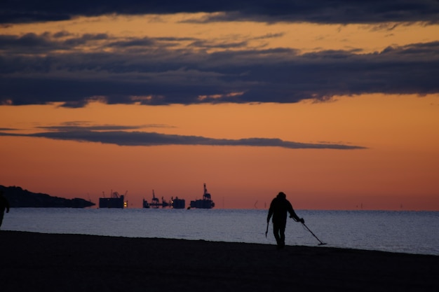 Uomo con metal detector al mattino, sulla spiaggia