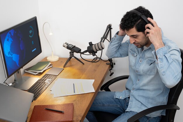 Uomo con microfono e cuffie che esegue un podcast in studio