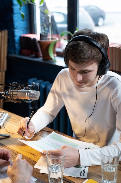 Uomo con microfono e cuffie che esegue un podcast in studio