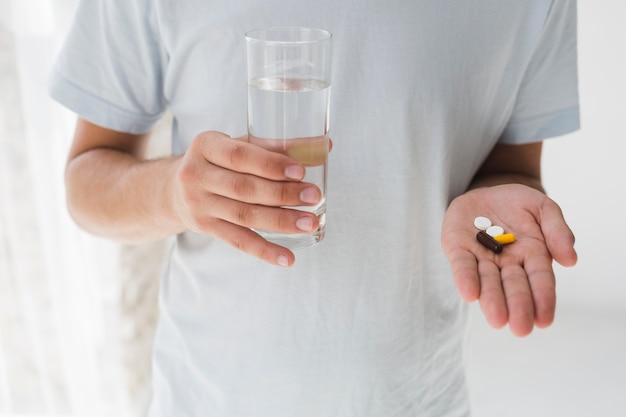 Uomo con pillole e acqua nelle mani