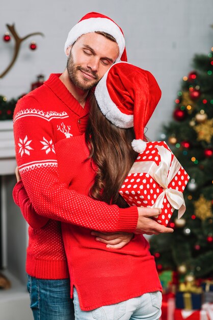 Uomo con regalo abbracciando la donna